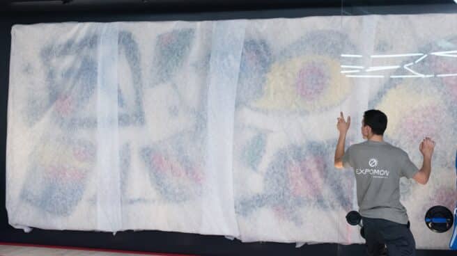 Un trabajador participa en la colocación del tapiz de Joan Miró y Josep Royo, en CaixaForum Madrid.