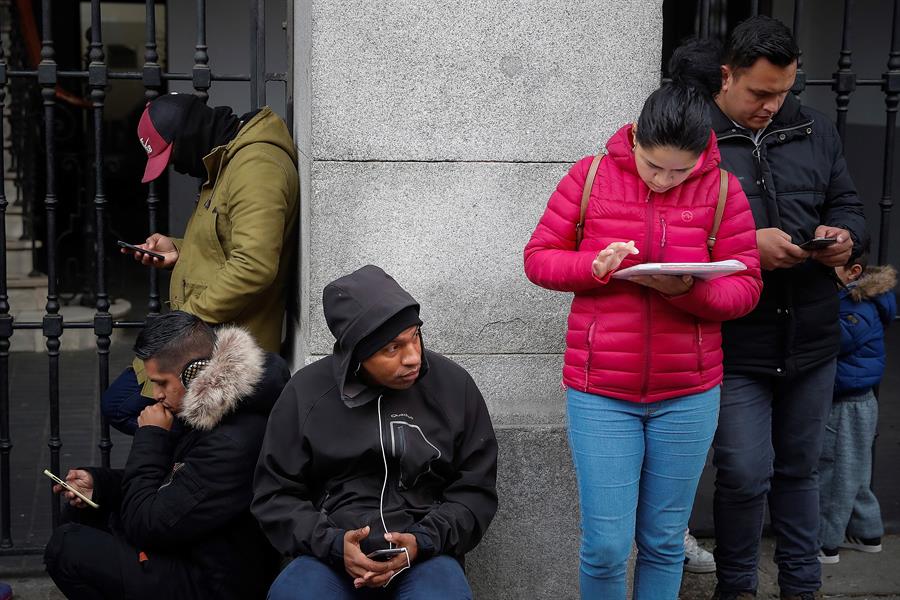 Imagen de archivo de demandantes de asilo denunciando trabas para conseguir una cita para el sistema de acogida e integración en Madrid, con voluntarios que les ayudan con sus propios móviles y portátiles.