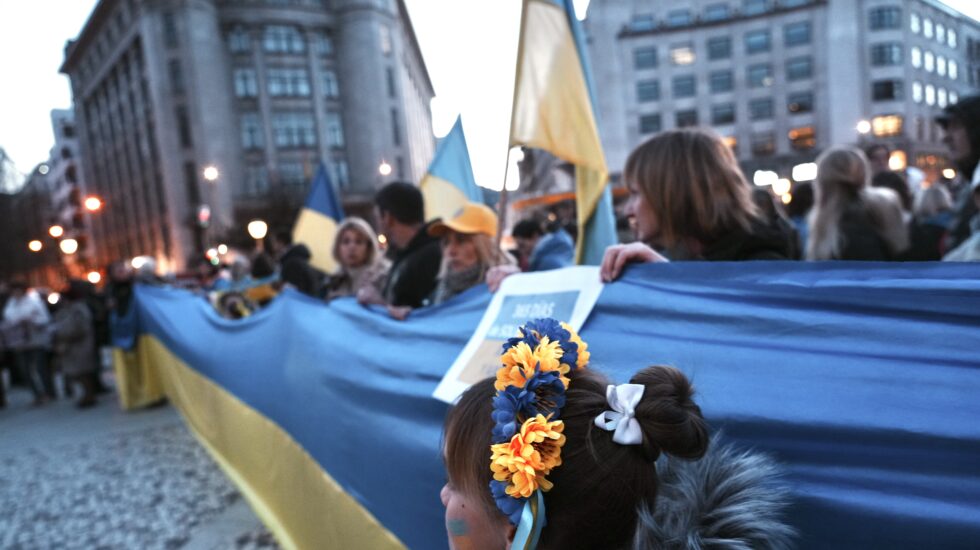 Un grupo de personas sujeta una bandera de Ucrania durante la manifestación contra la invasión rusa de Ucrania