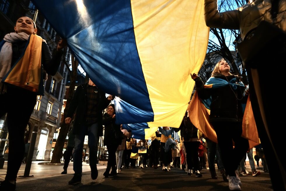 Un grupo de personas sujeta una bandera de Ucrania durante la manifestación contra la invasión rusa de Ucrania