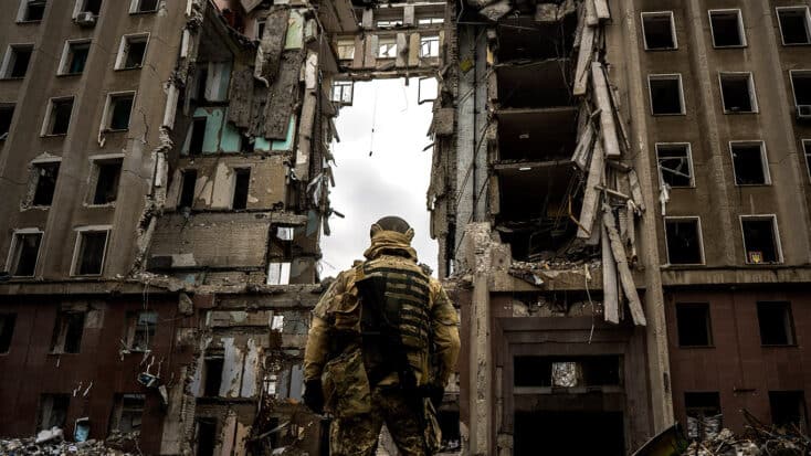 Un soldado ucraniano contempla la destrucción de un edificio bombardeado.