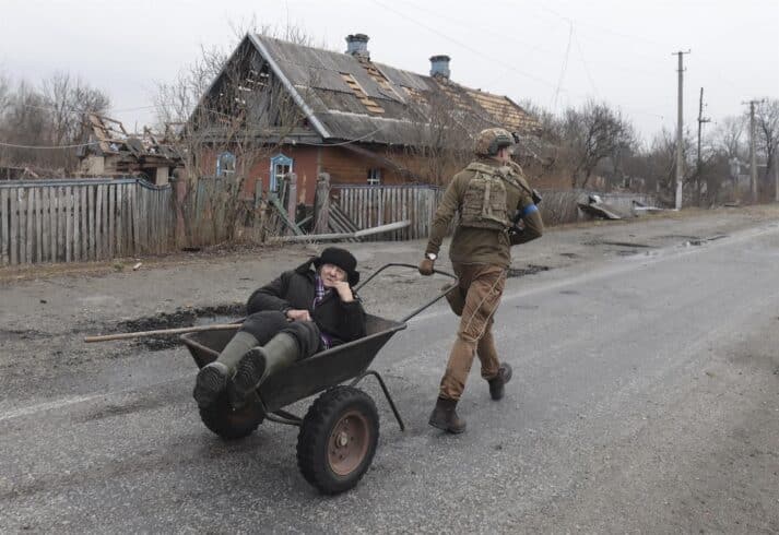 Un soldado ucraniano evacúa a un anciano de su hogar, destruido por las bombas, en Kiev.