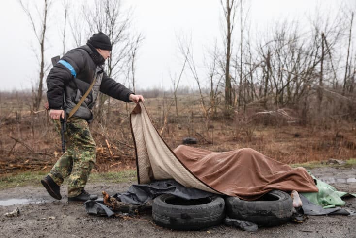 Un soldado ucraniano tapa varios cadáveres en Bucha.