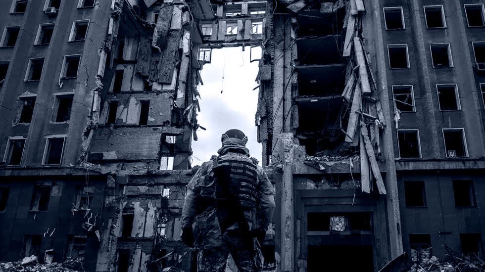 Soldado ucraniano ante un edificio bombardeado.
