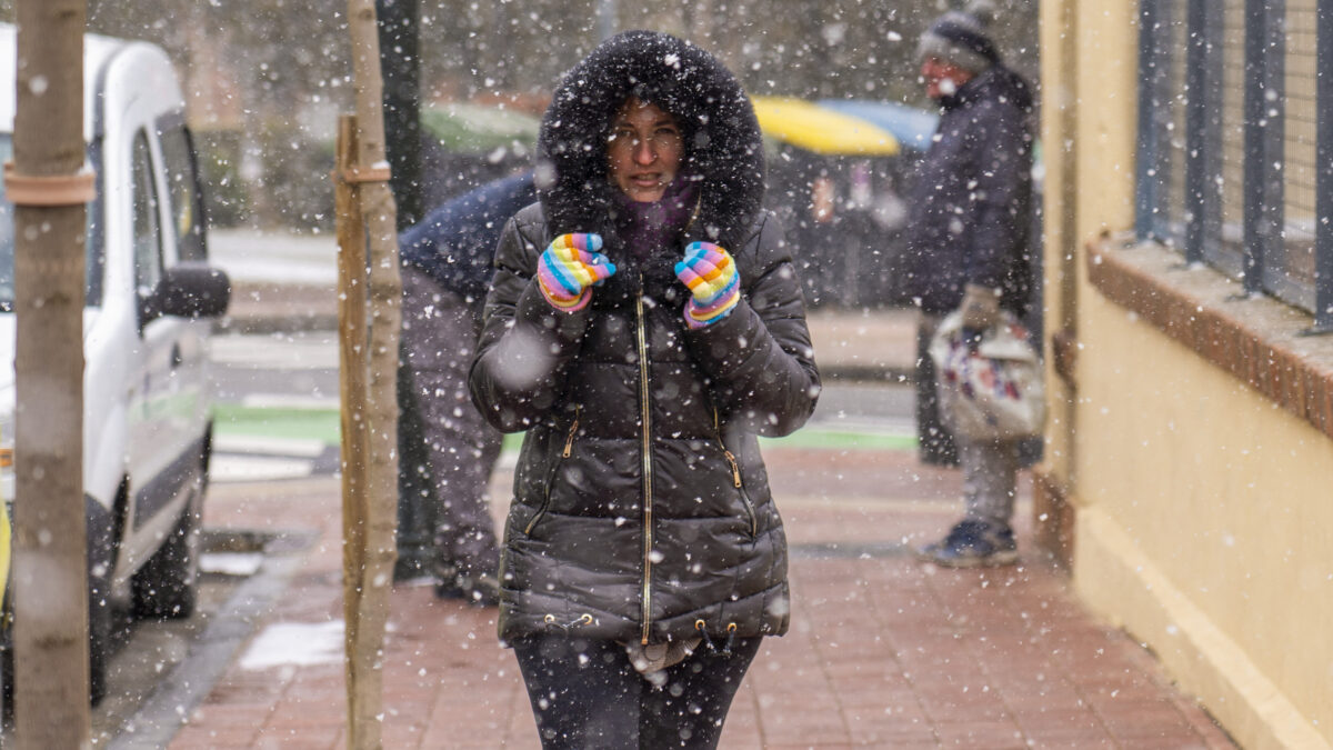 Una mujer se cubre de los copos de nieve en Teruel.