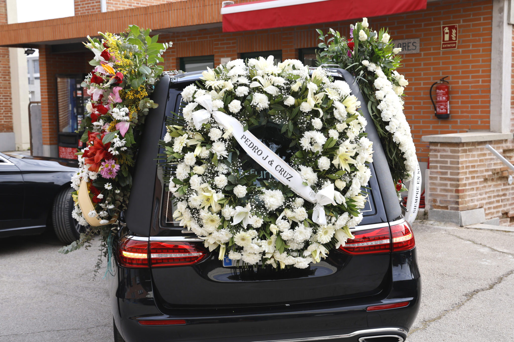El coche fúnebre de Luisa Rodríguez con una corona mandada por sus amigos Pedro J. Ramírez y Cruz Sánchez de Lara a su llegada al cementerio Sacramental de San Justo