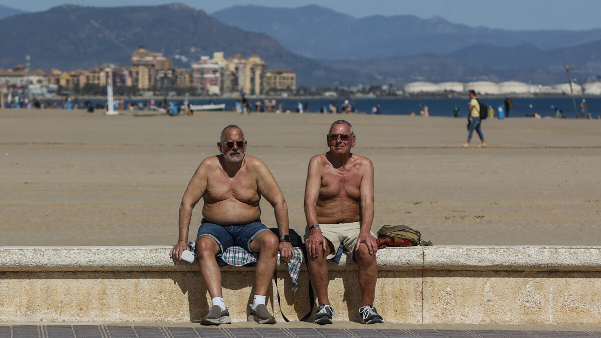 Dos hombres toman el sol en la playa de la Malvarrosa de Valencia.