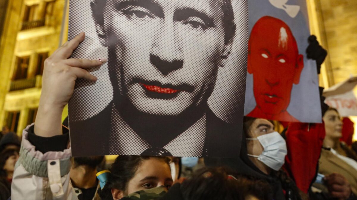 Una manifestante sujeta un cartel mofándose de Vladimir Putin en Tbilisi (Georgia).