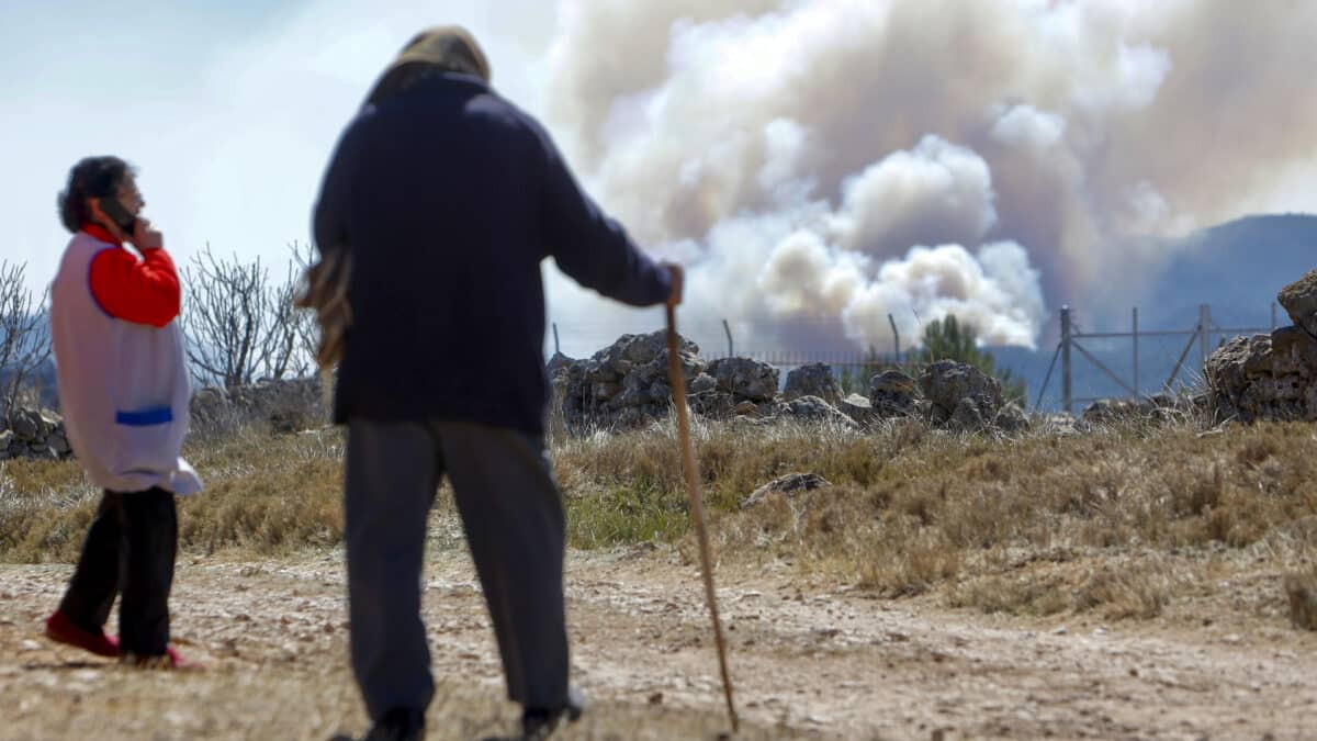 Dos vecinos observan el humo generado por el incendio de Villanuena de Viver (Castellón).