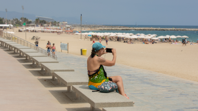 tiempo en semana santa 2023 calor Mujer disfrutando del buen tiempo en España en Semana Santa 2023 en la playa de Barcelona