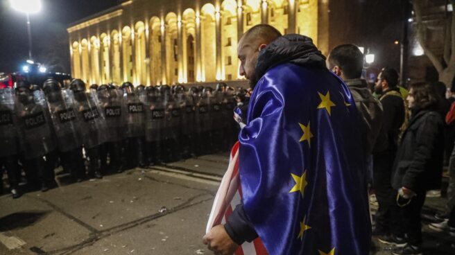 Un manifestante, con banderas de la Unión Europea y Estados Unidos, frente a los antidisturbios en Tbilisi.