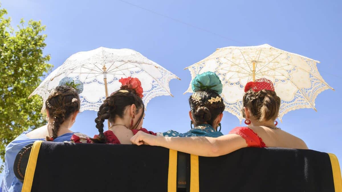 Unas jóvenes pasean en coche de caballos mientras se resguardan con dos sombrillas por las altas temperaturas que se están registrando estos días