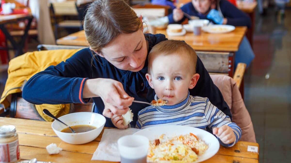 Una madre da de comer a su bebé en un comedor.