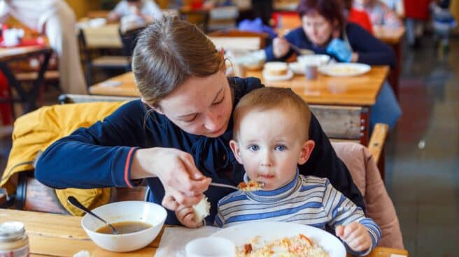 Una madre da de comer a su bebé en un comedor.