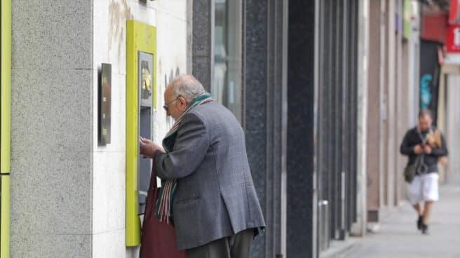 Un anciano saca dinero de un cajero en Madrid.