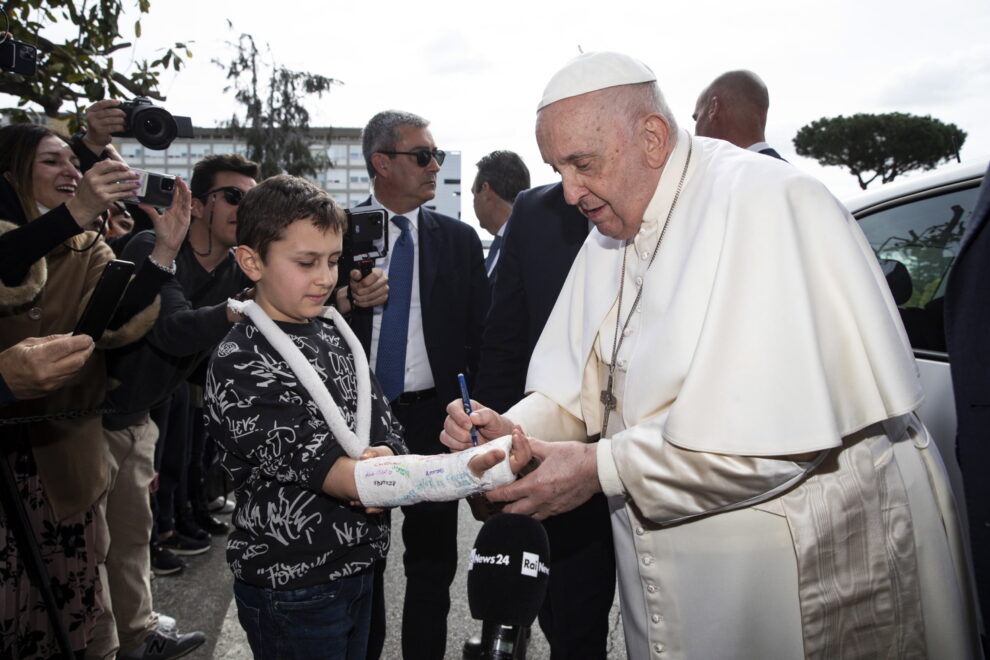 El Papa firma en la escayola de un niño tras salir del hospital.