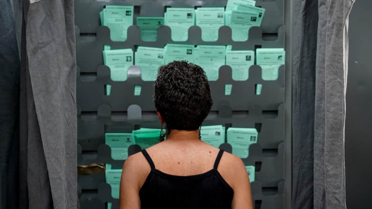 Una mujer observa las papeletas para ejercer su derecho al voto durante el día de las elecciones a la presidencia de la Junta de Andalucía