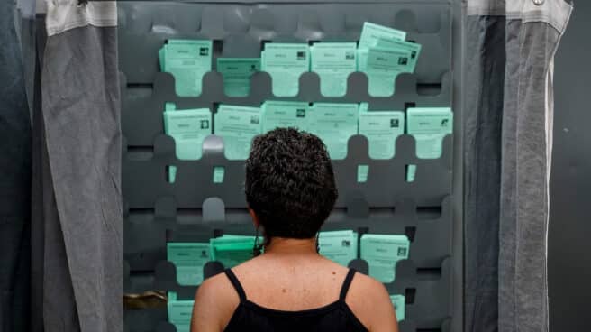 Una mujer observa las papeletas para ejercer su derecho al voto durante el día de las elecciones a la presidencia de la Junta de Andalucía