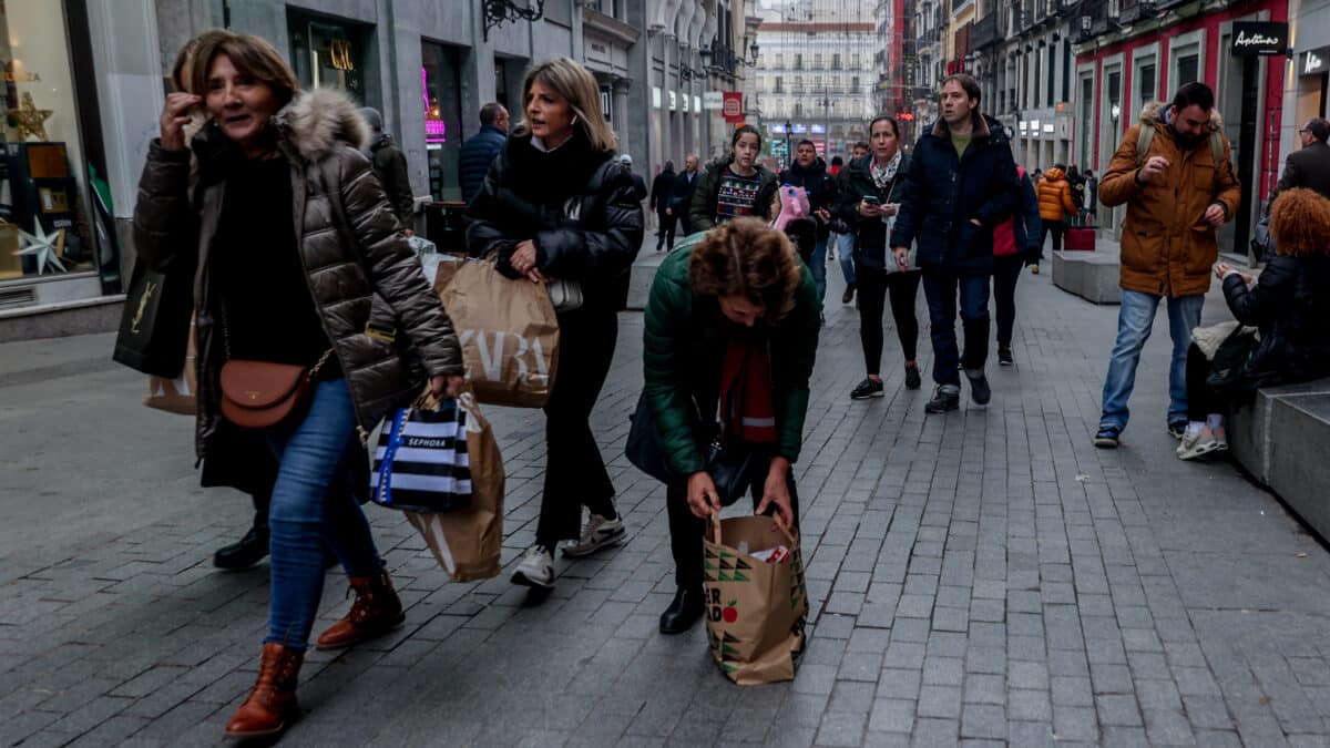 Varias personas pasean con bolsas en la calle Preciados de Madrid.