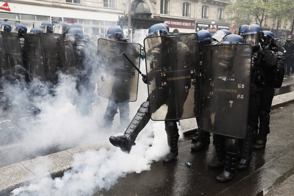 Un policía antidisturbios lanza una bomba lacrimógena durante los enfrentamientos en la marcha anual del Primero de Mayo en París, Francia