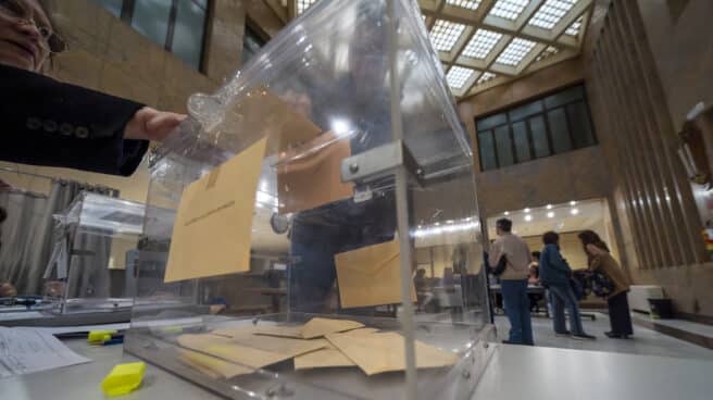 Un votante introduce tres sobres en la urna de un colegio de Almería Un hombre ejerce su derecho al voto en un colegio electoral