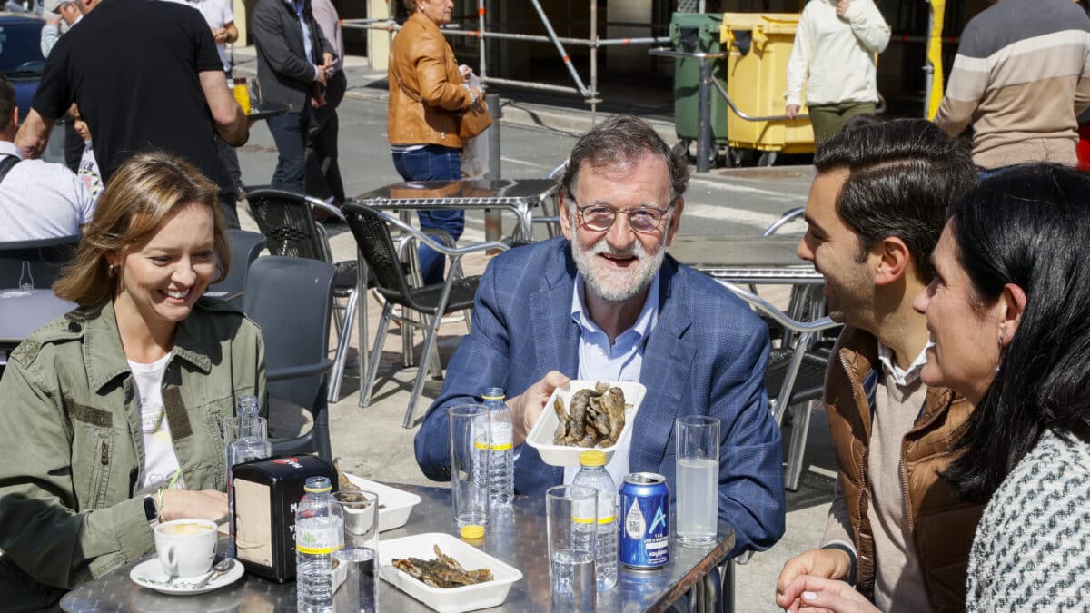 El expresidente del Gobierno, Mariano Rajoy, (c) junto al candidato local, Alex Doval (d), la conselelira de Familia, Fabiola García (izq) y la secretaria general del PP de Galicia, Paula Prado (d) degustan unas truchas en la Fiesta de la Trucha de Oroso