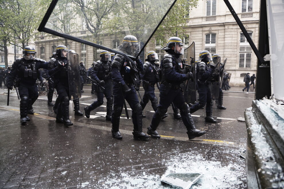 Un policía antidisturbios lanza una bomba lacrimógena durante los enfrentamientos en la marcha anual del Primero de Mayo en París, Francia