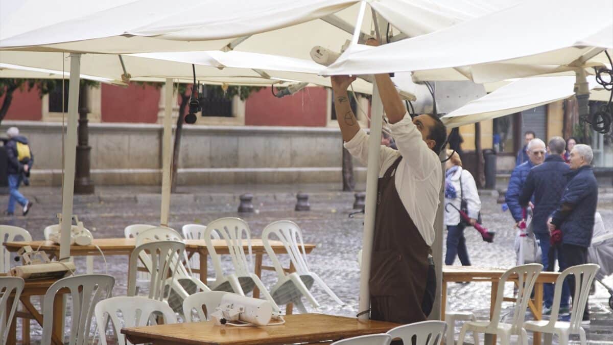 Un camarero pone los calefactores en una terraza en Sevilla.