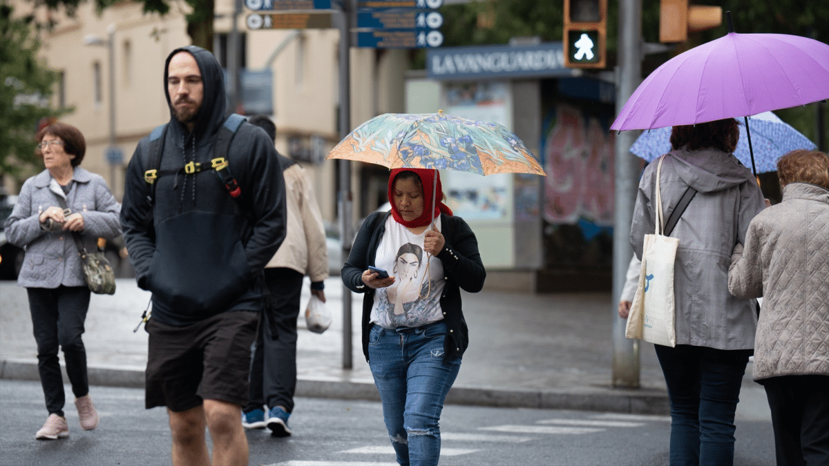 Personas paseando con paraguas contra la lluvia en mitad de una DANA en España