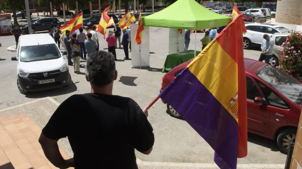 Un vecino de Marinaleda (Sevilla) ondea una bandera republicana en las puertas del ayuntamiento de la localidad frente al acto de campaña electoral realizado este viernes por militantes de Vox