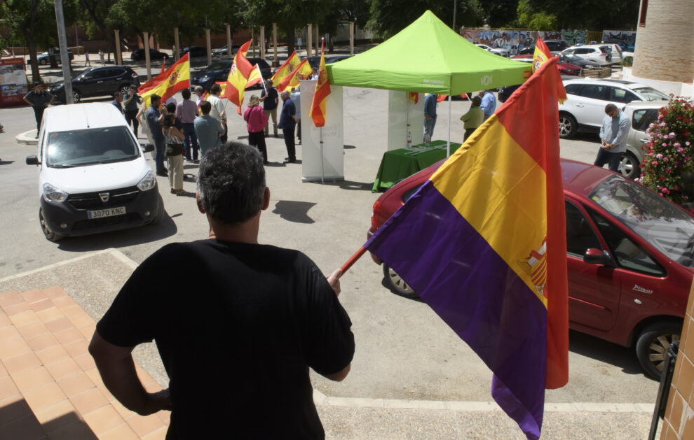 Un vecino de Marinaleda (Sevilla) ondea una bandera republicana en las puertas del ayuntamiento de la localidad frente al acto de campaña electoral realizado este viernes por militantes de Vox 