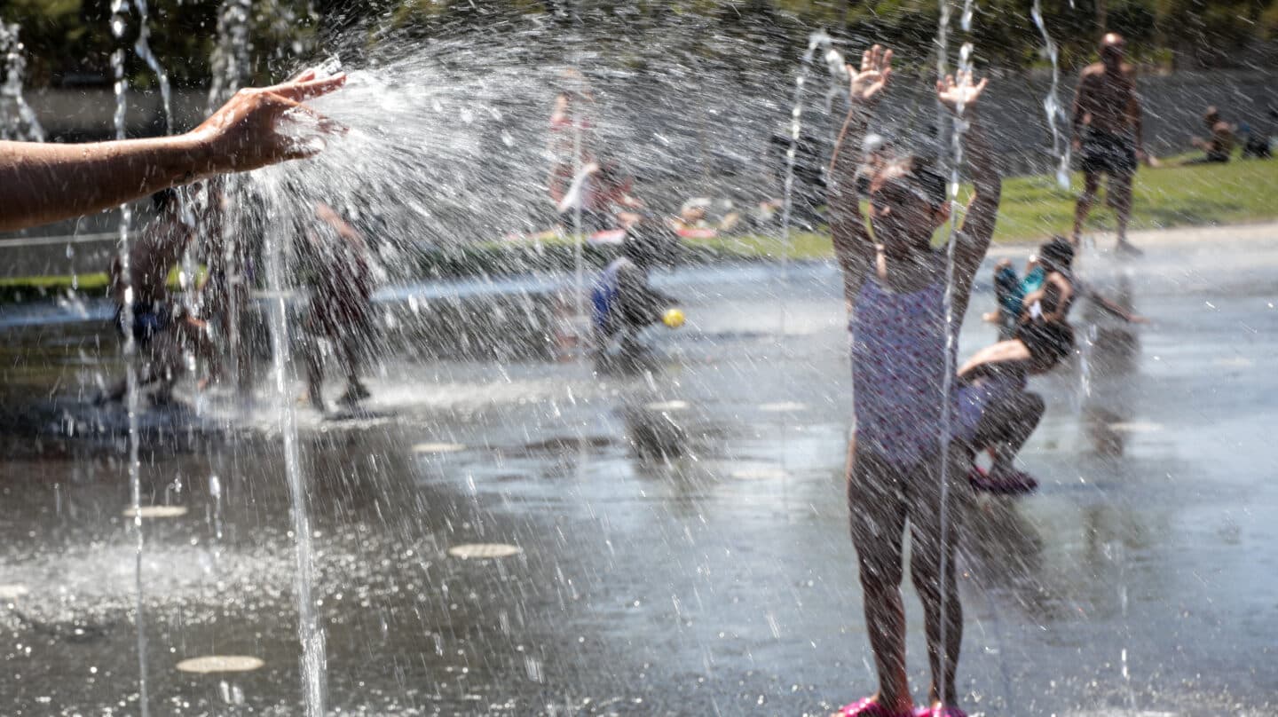 Varias personas, entre ellas niños, se refrescan en los chorros de Madrid Río en 2019.