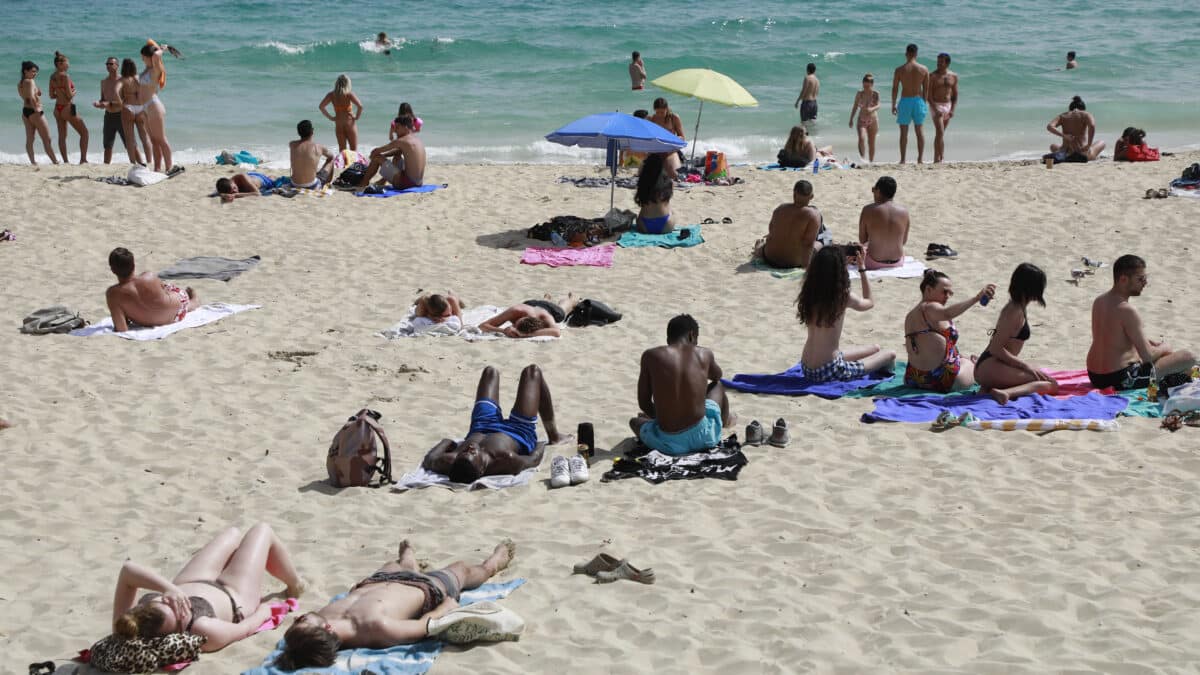 La gente se sienta en la playa en un día de primavera muy cálido en Palma
