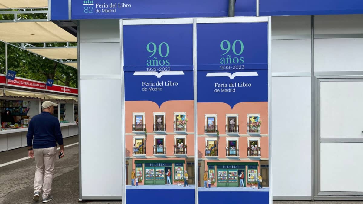 Un hombre camina junto al cartel de la Feria del Libro de Madrid