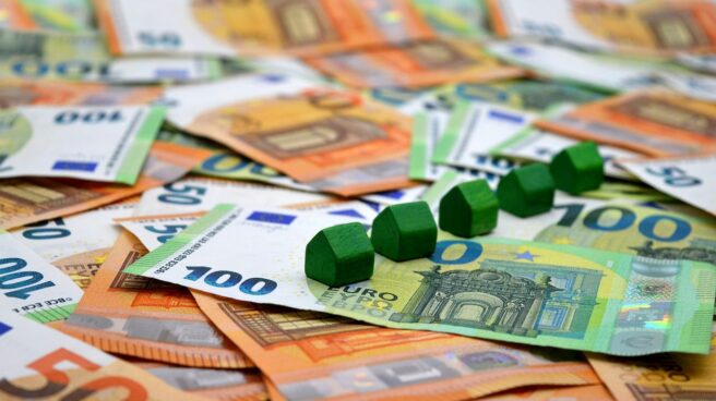 Unas casitas de madera encima de billetes de euros.