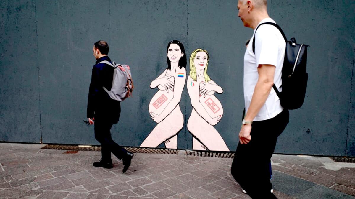 La gente camina junto a un mural de la primera ministra italiana Giorgia Meloni (R) y la líder del PD Elly Schlein, retratada por el artista 'aleXsandro Palombo' en Milán, Italia