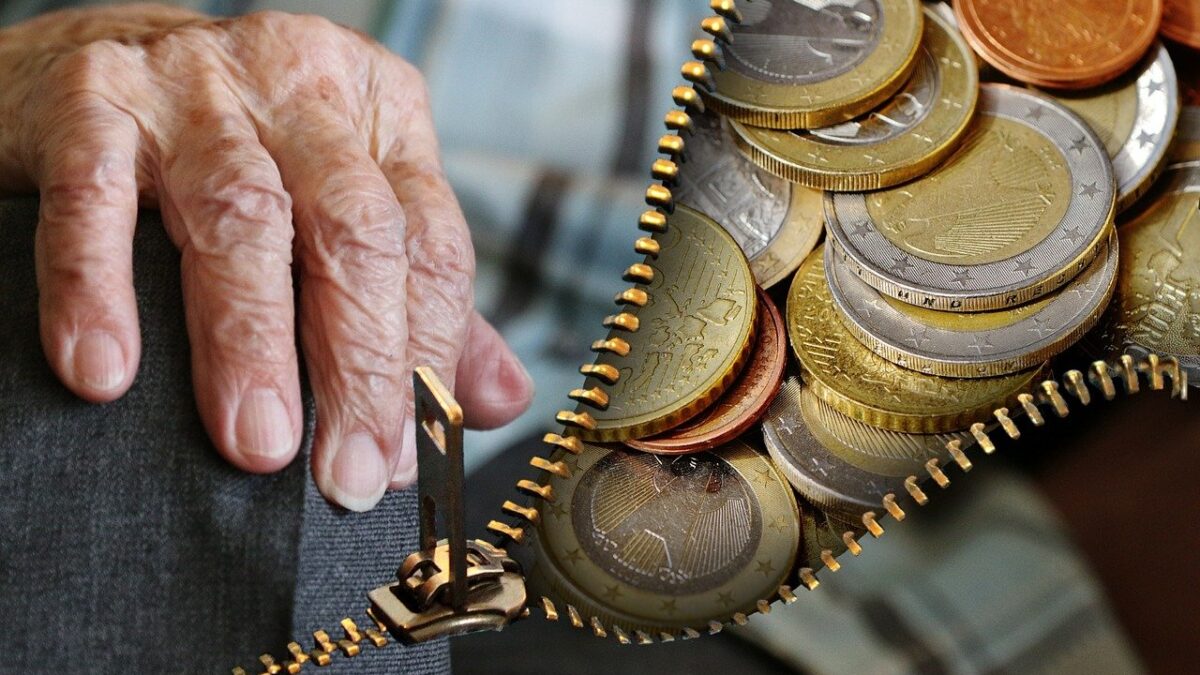 Una mano de una persona mayor junto a monedas de euro.