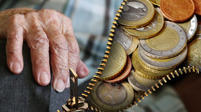 An elderly man's hand next to euro coins.