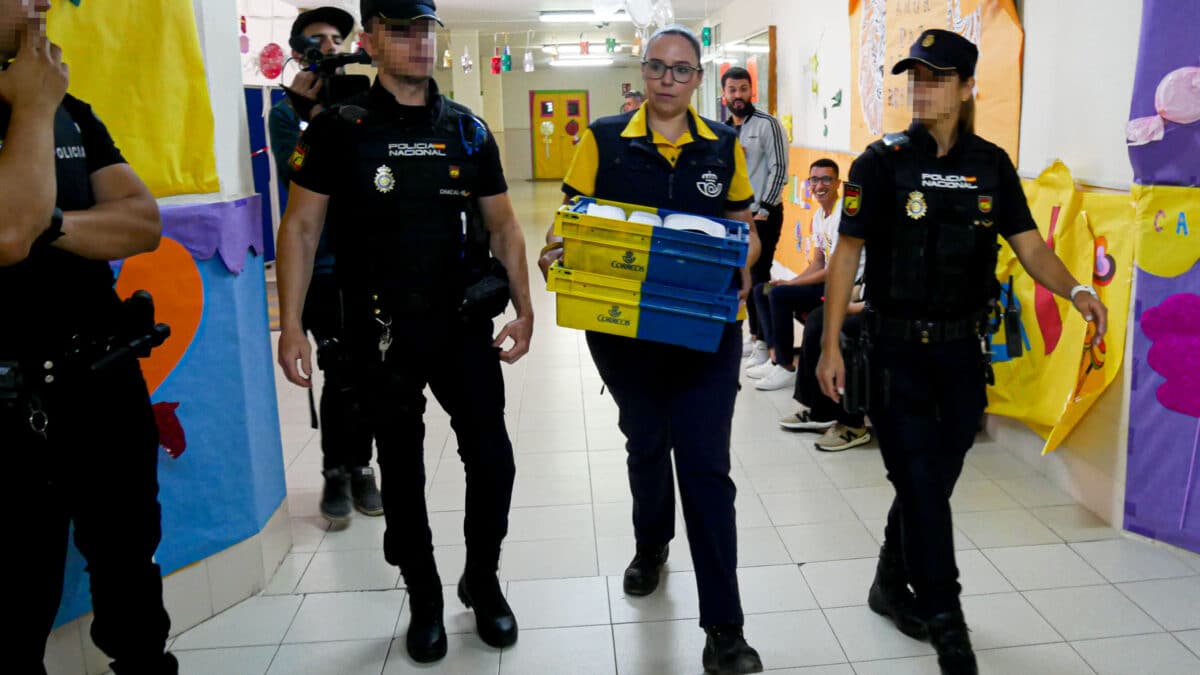 Dispositivo de Seguridad en Colegio León Solá de Melilla en el que varios agentes escoltan a la funcionaria de Correos a la mesa electoral para entregar los votos por correo.