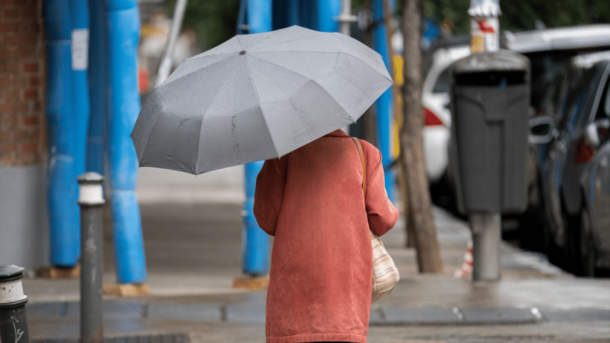 Una mujer pasea por una calle con un paraguas con la reciente temporada de lluvias fuertes que afectan a muchas zonas de España y que han dejado alerta amarilla y naranja por el peligro.