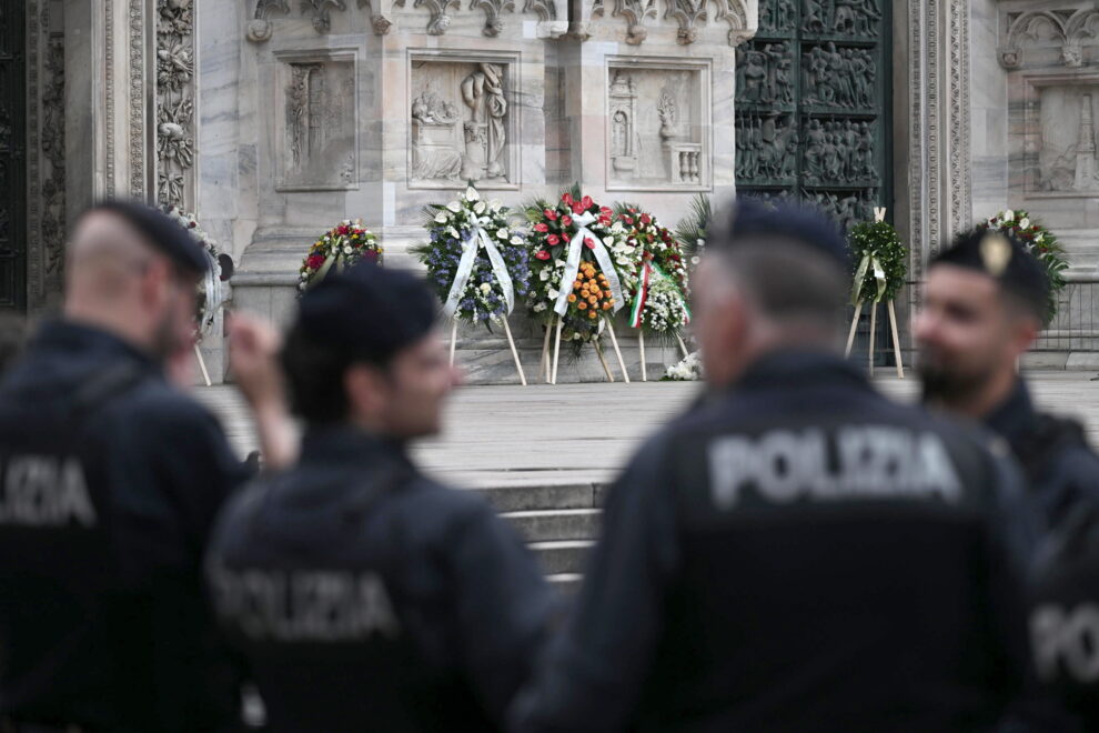 Un grupo de policías cerca de las guirnaldas colocadas en el exterior de la Catedral de Milán (Duomo) antes del funeral de estado del exprimer ministro italiano