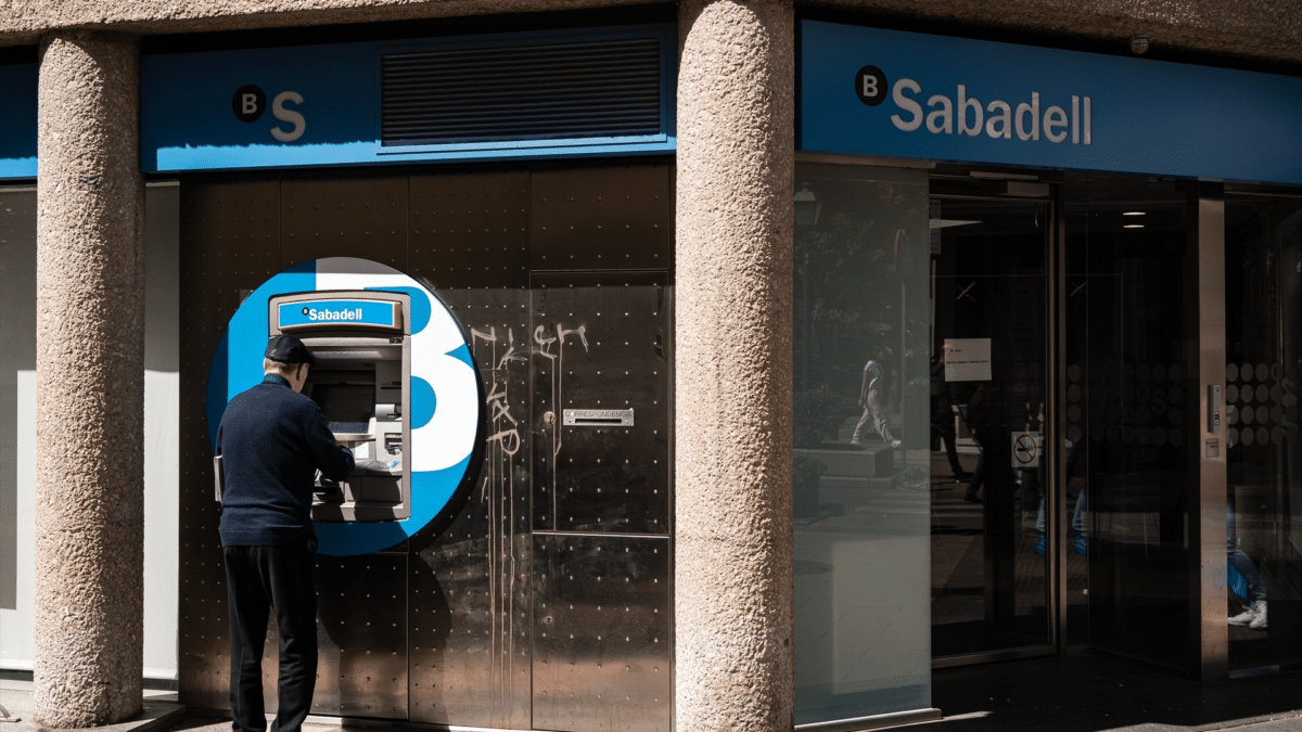 Un hombre en el cajero de la entidad bancaria de Sabadell, que pretende cobrar su pensión de junio 2023