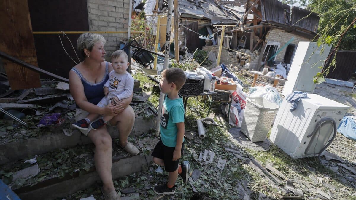 Una mujer y sus hijos entre los escombros de su hogar tras el impacto de un cohete ruso en la localidad de Stari Petrivtsi, en los alrededores de Kiev (Ucrania).