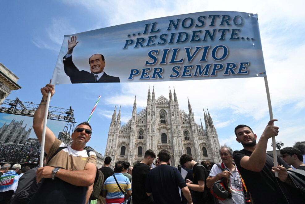 Dos personas sostienen una pancarta que dice '...nuestro presidente, Silvio para siempre' mientras esperan fuera de la Catedral de Milán (Duomo)