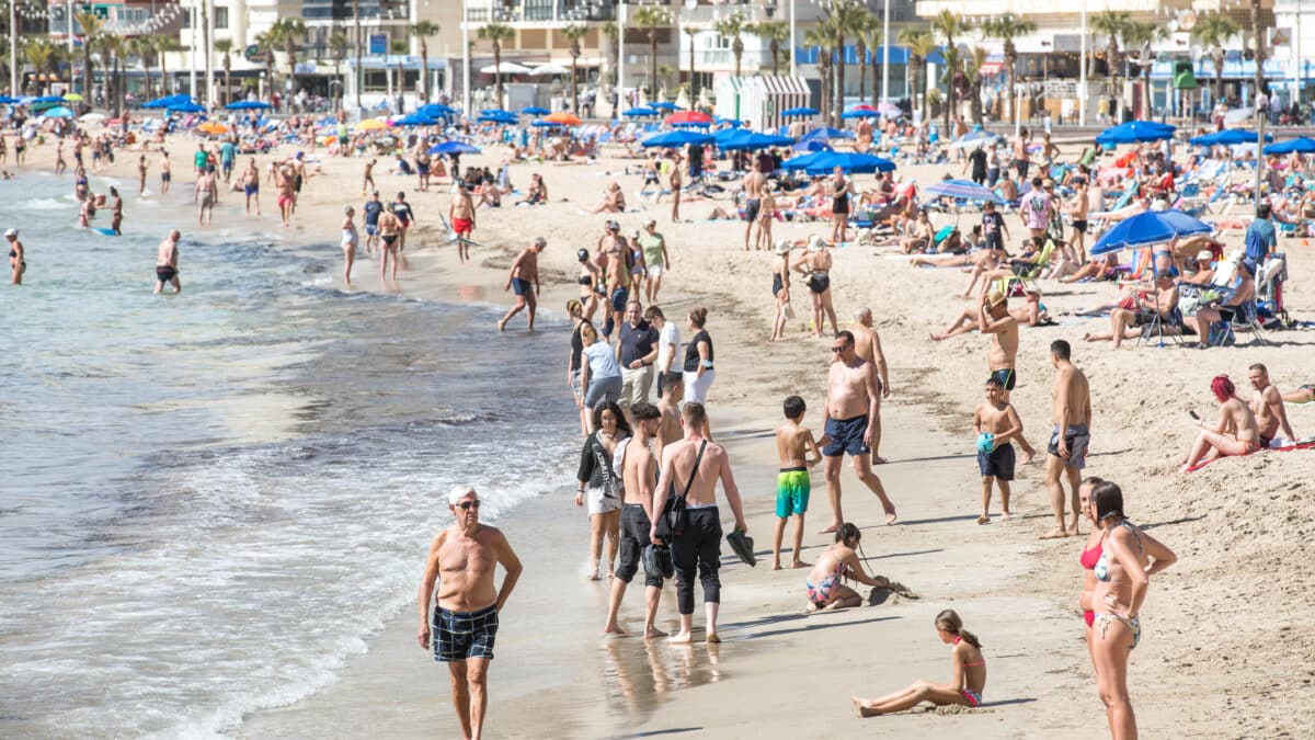 Numerosas personas se bañan y toman el sol en la playa de Poniente,