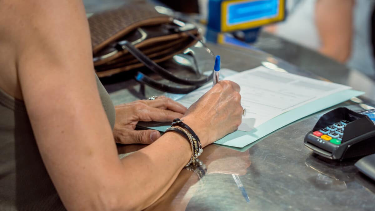 Una persona rellena unos documentos tras solicitar el voto por correo en el Edificio de correos