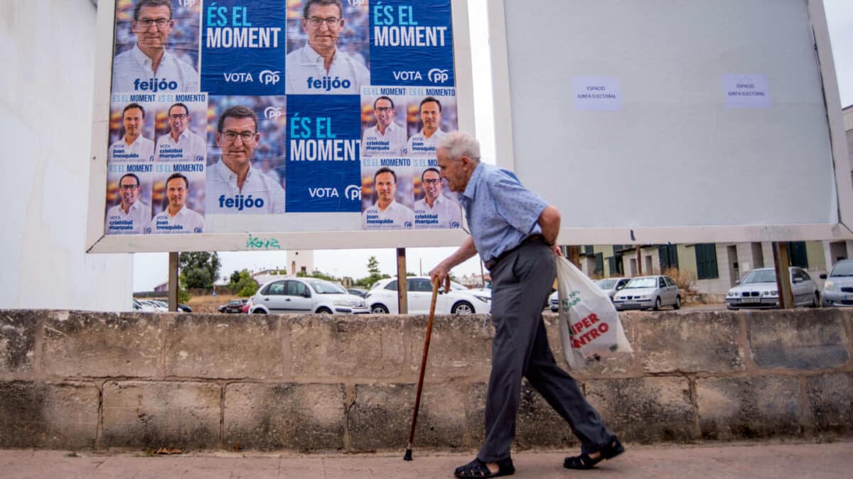 Un hombre camina junto a la publicidad electoral del Partido Popular en Mahón, Menorca, en el comienzo oficial de la campaña electoral