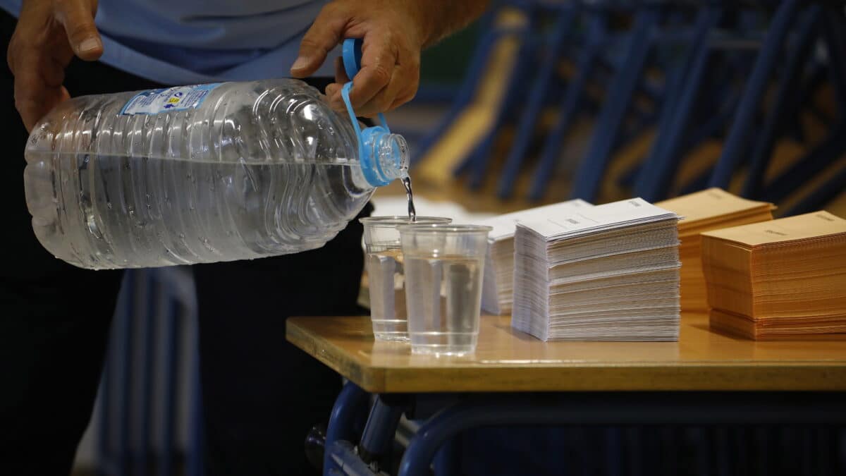 Un hombre llena vasos de agua en el colegio electoral en la Casa de la Juventud en Écija (Sevilla)