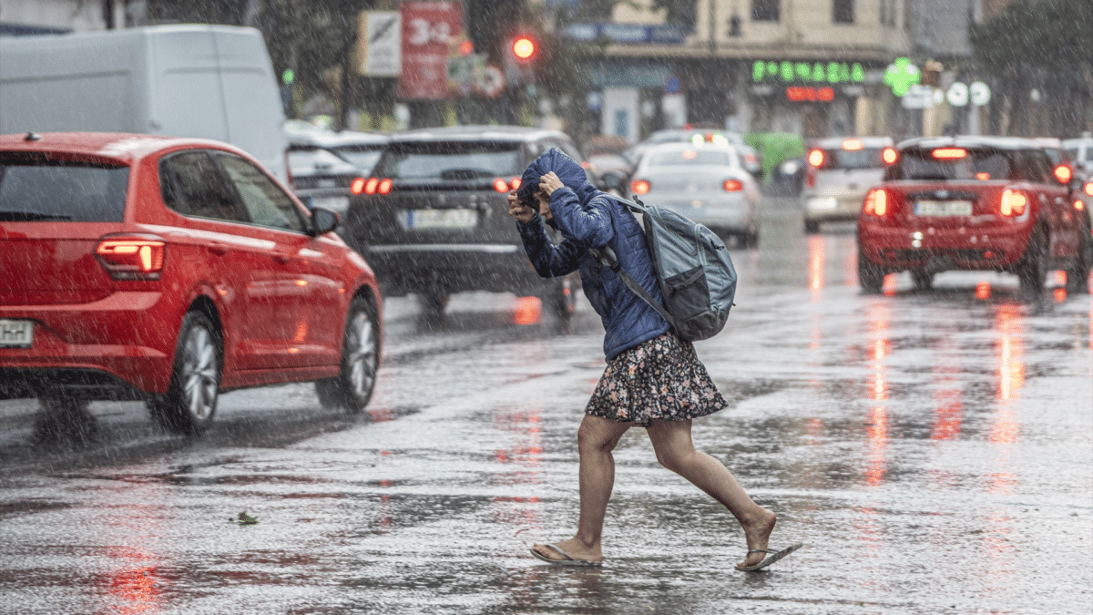 Una mujer anda por la calle bajo la lluvia tras tormentas intensas que dejará la última DANA de julio