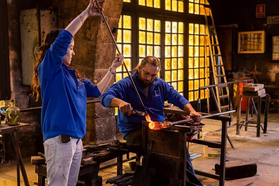 Dos artesanos trabajan en el proceso de elaboración de la fábrica de vidrios.
